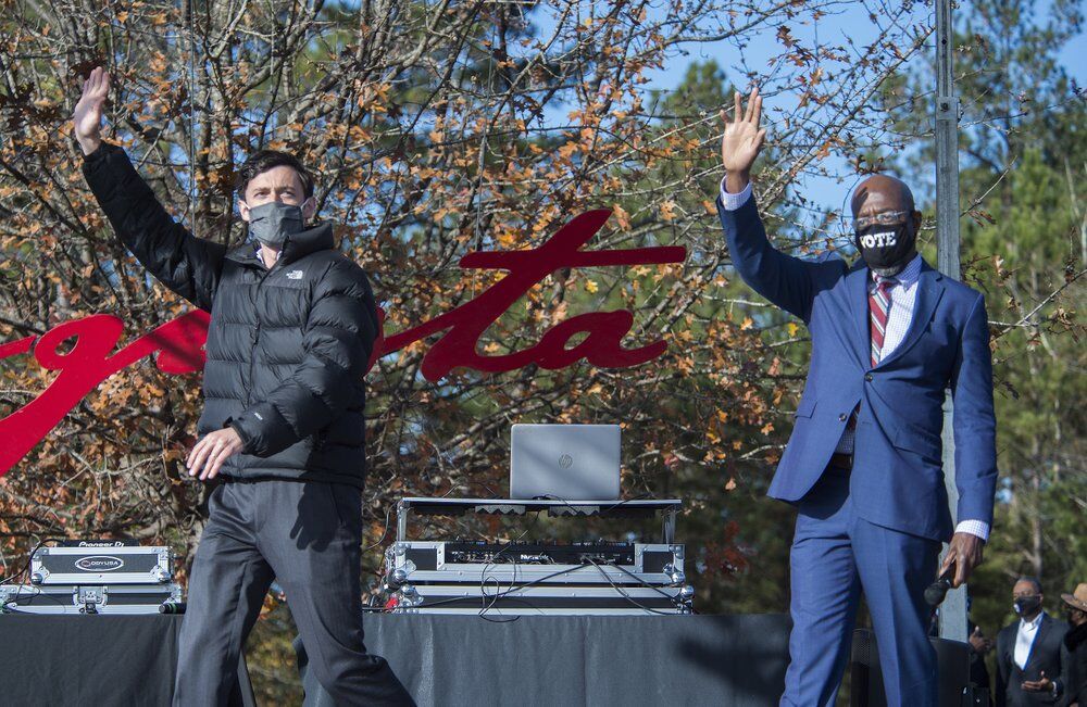 Jon Ossoff, left, and Rev. Raphael Warnock wave to the crowd